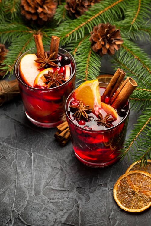 Two Glasses of Christmas Mulled Red Wine with Decoration, Orange, Cinnamon and Fir Tree on rustic background